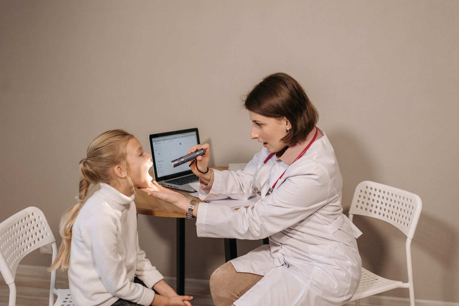 Médica atendiendo a una niña con una computadora en el consultorio